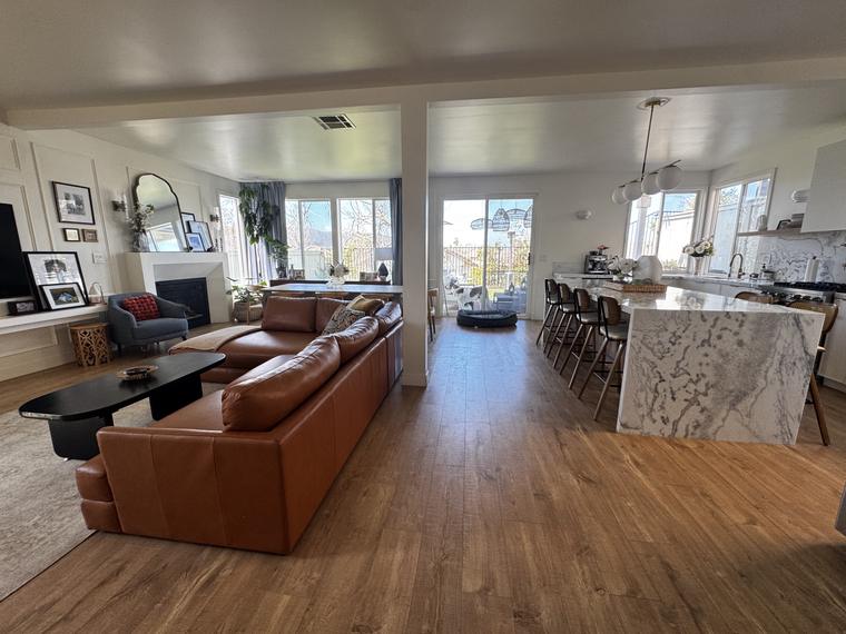 Open great room in a remodeled Carmel Mountain home with a marble waterfall kitchen island and leather sectional