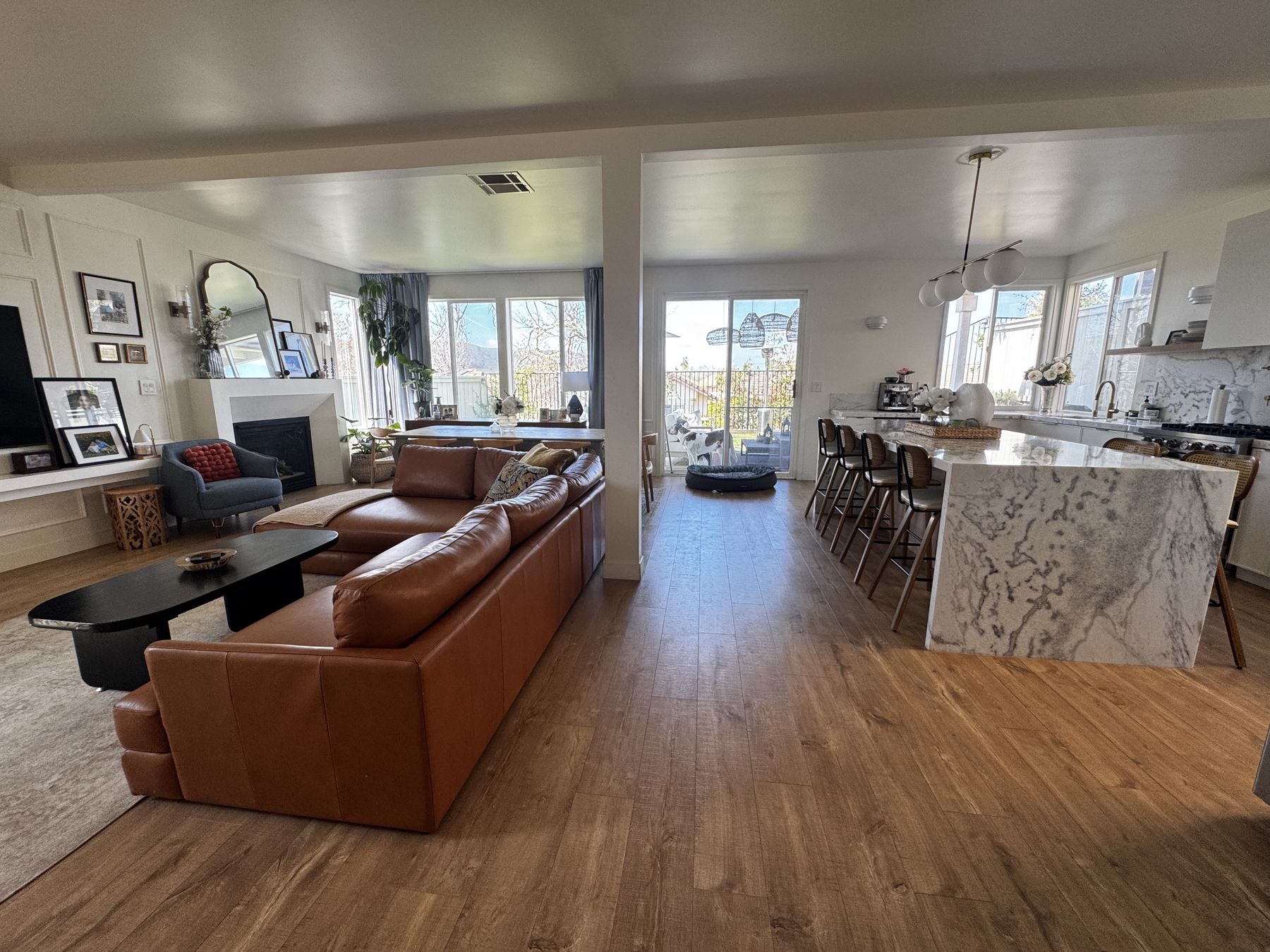 Open great room in a remodeled Carmel Mountain home with a marble waterfall kitchen island and leather sectional
