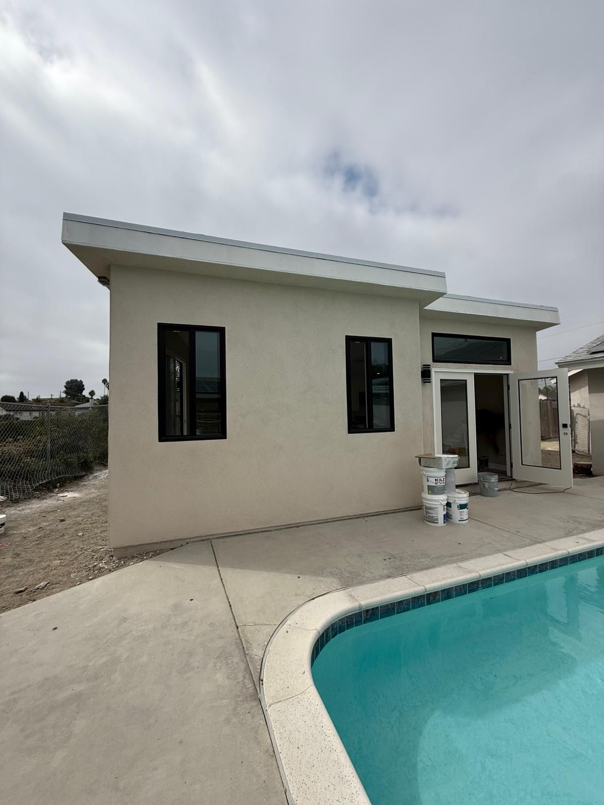 Detached Clairemont ADU beside the backyard pool, with black-framed windows and French doors