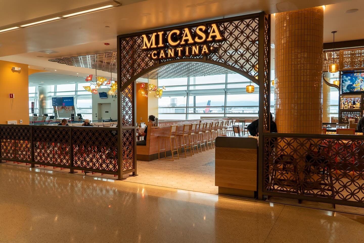 Mi Casa Cantina entrance with carved wood screens and lighted signage at San José airport