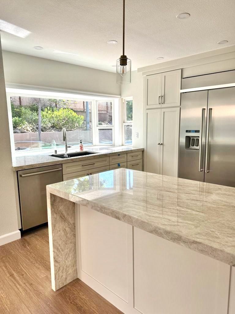 Rancho Peñasquitos kitchen with a stone waterfall peninsula, white shaker cabinets and a built-in refrigerator