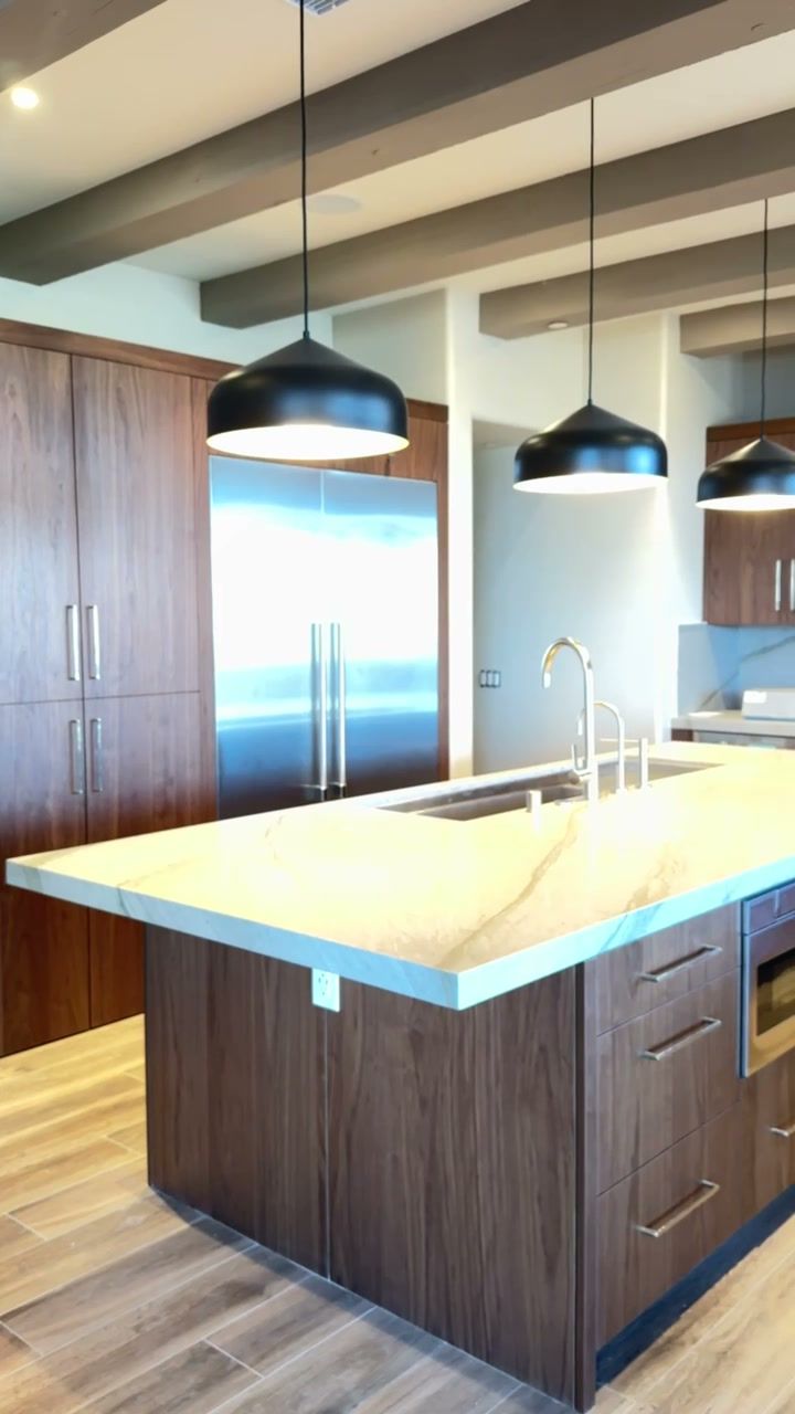 Walnut kitchen cabinetry and a waterfall island under black pendant lights in a remodeled Rancho Santa Fe home